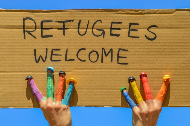 Refugees welcome - Hände mit bunten Fingern halten ein Pappschild mit der Aufschrift "Flüchtlinge willkommen"